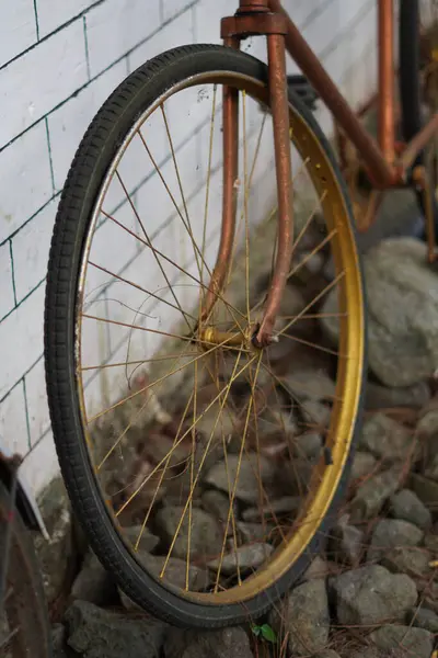 Beyaz tuğlalı bir duvara yaslanmış antik altın bisiklet tekerlekleri ve kaldırımlı bir sokak