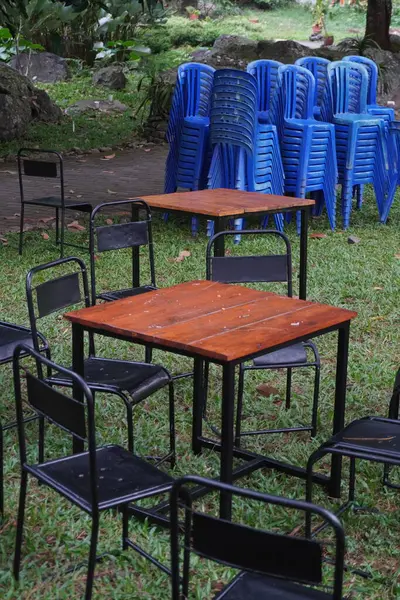 stock image Wooden table with iron legs between black iron chairs in a field