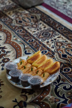 Kırmızı halı arka planında geleneksel Endonezya atıştırmalıkları kusmuk, sosis solosu ve çikolatalı puding.