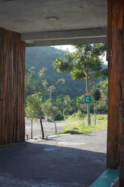 A small tunnel as an entrance to a tourist area with a background of trees and hills. clipart