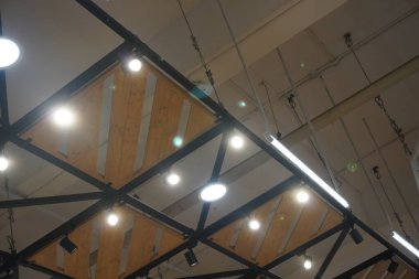 Bir alışveriş merkezinde demir ve ahşaptan yapılmış tavana bağlı yuvarlak ışıklar.