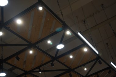 Bir alışveriş merkezinde demir ve ahşaptan yapılmış tavana bağlı yuvarlak ışıklar.