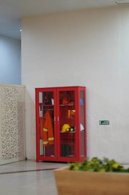 Giysiler, şapkalar ve diğer aletler gibi itfaiye ekipmanları bir alışveriş merkezindeki cam dolapta bulunmaktadır.