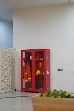 Giysiler, şapkalar ve diğer aletler gibi itfaiye ekipmanları bir alışveriş merkezindeki cam dolapta bulunmaktadır.
