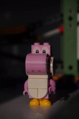  Lego pembe Yoshi minyatür figürü. Güneş ışığı ve bulanık arkaplan önünde çekilmiş.