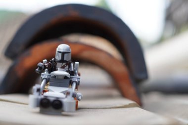 Lego minyatürleri Mandalorian ve Bebek Yoda (Grogu) bulanık bir arkaplan ile tünelden geçiyorlar