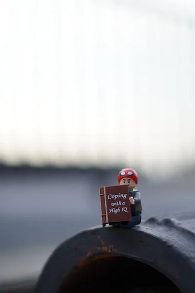 Lego minyatürü Peter Parker oturuyor ve bulanık arkaplanı olan bir kitap okuyor ve boşluğu kopyalıyor