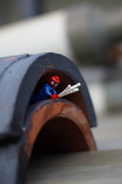 Lego minifigure spiderman crawling under a tunnel with a blurred background clipart