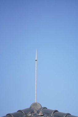 Arka plan olarak mavi gökyüzü olan bir evin çatısına bir yıldırım koruma cihazı yerleştirildi.