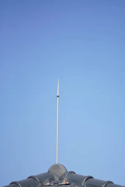 stock image A lightning protection device installed on the roof tiles of a house with a blue sky as a background