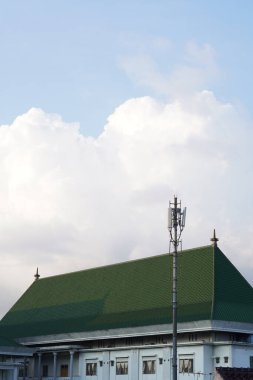 A building with a green roof with clear sky and clouds clipart