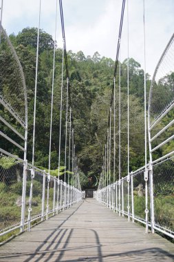 Gün boyunca sakin bir turistik bölgede demir parmaklıklardan yapılmış asma köprü.