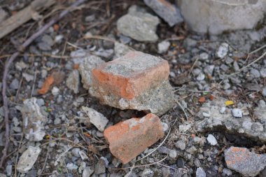 Kırık kırmızı tuğlalar çakılların üzerine kazınmış.