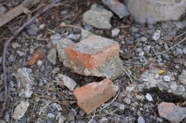 Kırık kırmızı tuğlalar çakılların üzerine kazınmış.