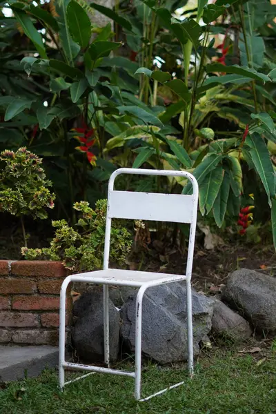 stock image Empty white chairs with a green garden and rocky background