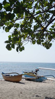  Gün boyunca denize bakan ve üzerinde yapraklar olan iki geleneksel tekne Situbondo 'nun Pasir Putih plajı bölgesinde sahile yerleştirildi.
