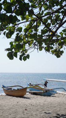  Gün boyunca denize bakan ve üzerinde yapraklar olan iki geleneksel tekne Situbondo 'nun Pasir Putih plajı bölgesinde sahile yerleştirildi.