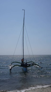 Gündüz vakti Pasir Putih Situbondo sahilinde dinlenen geleneksel bir tekne.
