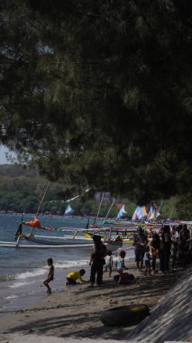 Situbondo 'nun Beyaz Kum Sahili' ne gelen ziyaretçiler gün boyunca sahilde oynuyorlar.