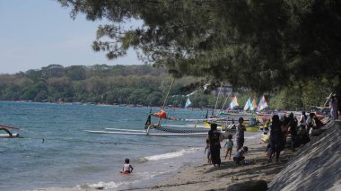 Situbondo 'nun Beyaz Kum Sahili' ne gelen ziyaretçiler gün boyunca sahilde oynuyorlar.