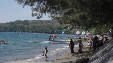 Situbondo 'nun Beyaz Kum Sahili' ne gelen ziyaretçiler gün boyunca sahilde oynuyorlar.