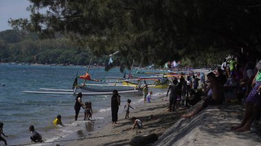 Situbondo 'nun Beyaz Kum Sahili' ne gelen ziyaretçiler gün boyunca sahilde oynuyorlar.