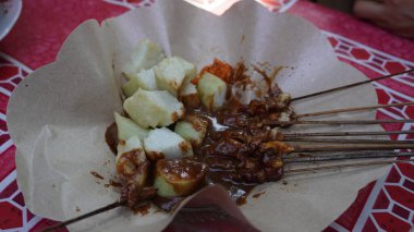 Endonezya yemeği, yani fıstık soslu tavuk satay ve kahverengi kağıtlı lontong.