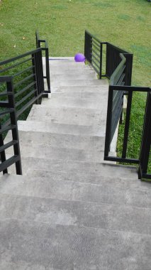 Düzensiz görünen bir endüstriyel konsepte sahip siyah demir merdiven büyük bir bahçede oyun oynamak için kullanılır.