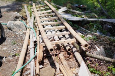 Bambu merdivenleri bir binanın yapım aşamasından bambu yığınlarının üzerinde.