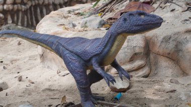 Kumda yürüyen küçük bir dinozor heykeli. 