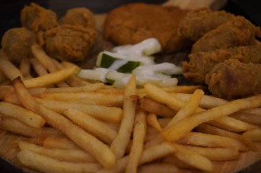 Patates kızartması, nugget, kızarmış sosis, kızarmış tavuk ve ortada turşudan oluşan karışık tabaklar.