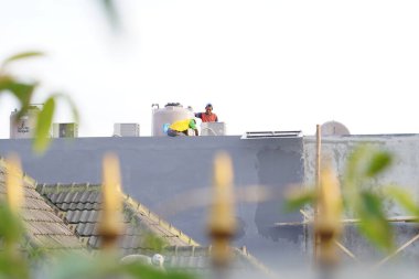 Öğleden sonra bir evin çatısında çalışan iki işçi.