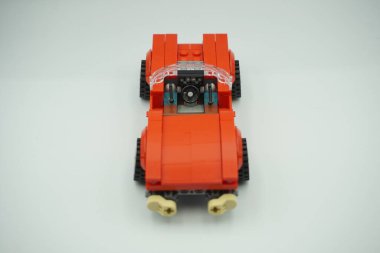 Lego tuğlaları beyaz arka planda çatısı olmayan kırmızı renkli oyuncak araba.