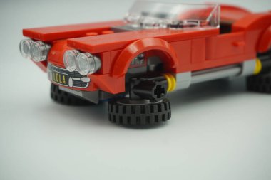 Red car bricks toy from the side with upside down wheels and white background clipart