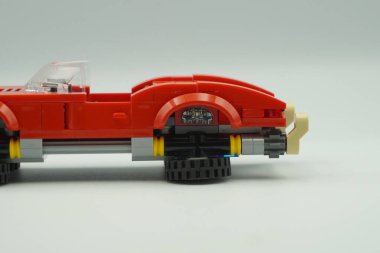 Red car bricks toy from the side with upside down wheels and white background clipart