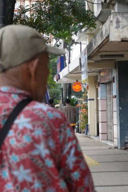 Yaşlı bir adam sağına bakarken kaldırımda yürüyordu.