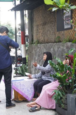 Para toplayan yaşlı bir kadın turistik bir etkinliğin girişinden içeri girdi.