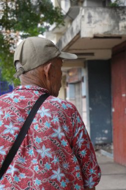 Yaşlı bir adam sağına bakarken kaldırımda yürüyordu.