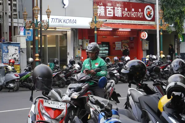  Endonezyalı motosikletli taksi şoförü yolun kenarında duruyor.