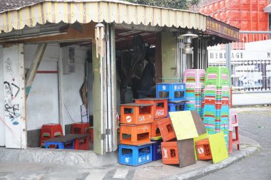 Yolun kenarındaki eski bir dükkanda boş içki sandıkları ve kısa plastik sandalyeler.