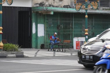 Kayutangan, Malang 'da kaldırımda tek başına oturan bir park görevlisi.