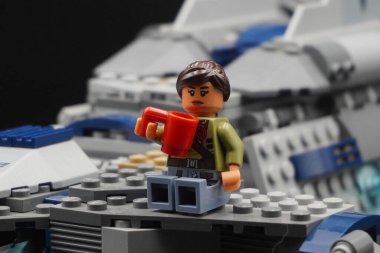 Yıldız Savaşları 'ndan kalma Lego figürü elinde cam olan bir uzay gemisinin kanadında oturuyor.