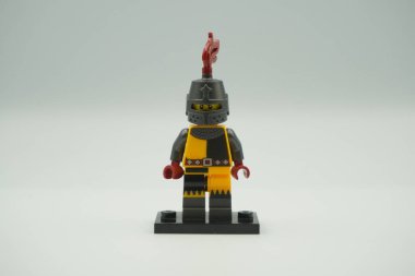 Beyaz arka planda sarı ve gri kostümlü oyuncak tuğlalardan Lego Turnuvası Şövalyesi mini figürü.