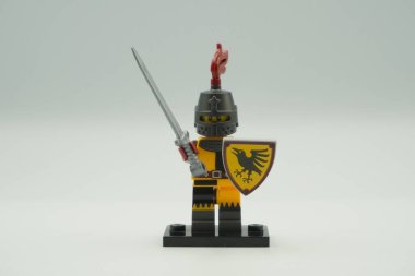 Beyaz arka planda sarı ve gri kostümlü oyuncak tuğlalardan Lego Turnuvası Şövalyesi mini figürü.