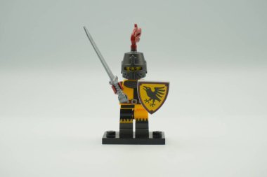 Beyaz arka planda sarı ve gri kostümlü oyuncak tuğlalardan Lego Turnuvası Şövalyesi mini figürü.