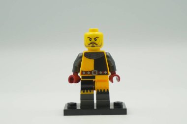 Beyaz arka planda sarı ve gri kostümlü oyuncak tuğlalardan Lego Turnuvası Şövalyesi mini figürü.