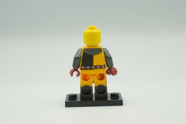 Beyaz arka planda sarı ve gri kostümlü oyuncak tuğlalardan Lego Turnuvası Şövalyesi mini figürü.