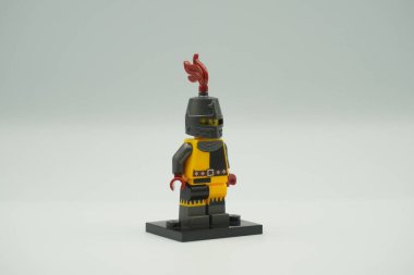 Beyaz arka planda sarı ve gri kostümlü oyuncak tuğlalardan Lego Turnuvası Şövalyesi mini figürü.