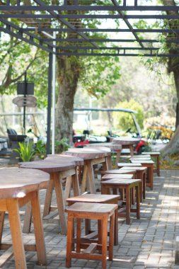 Wooden chairs and tables in a deserted outdoor cafe without people clipart