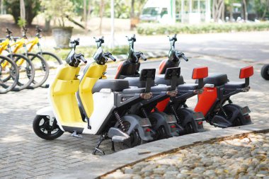 Renkli elektrikli motosikletler ziyaretçilere kiralanmak üzere turistik bir yere dizildiler.